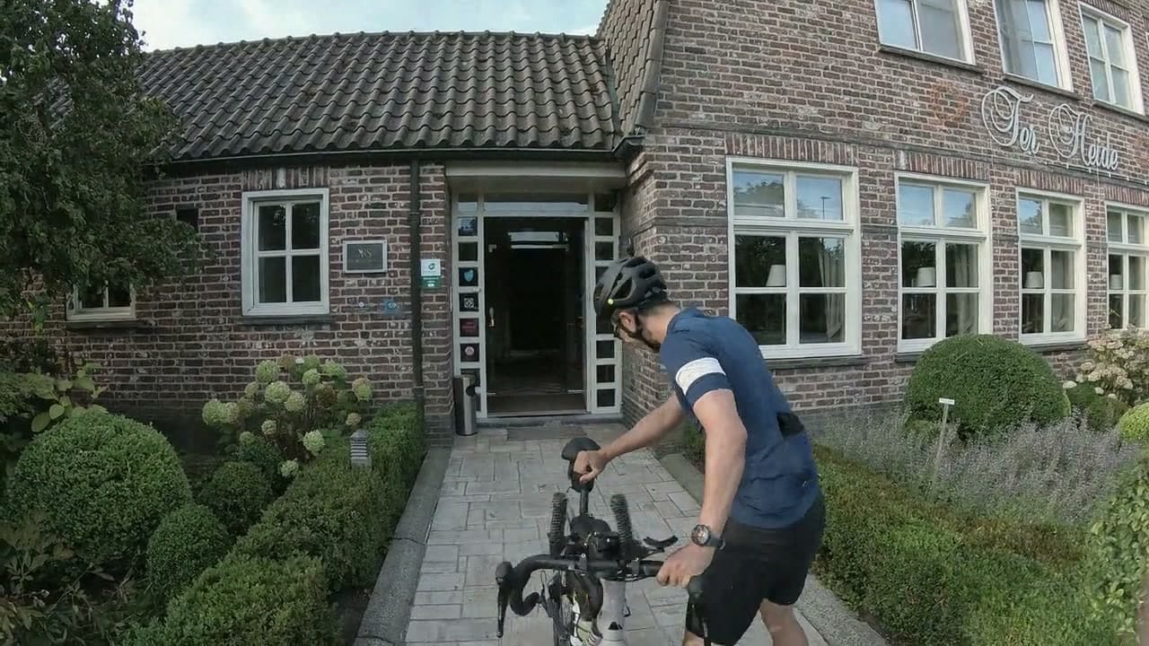 Rider guiding a loaded road bike away from a hotel entrance